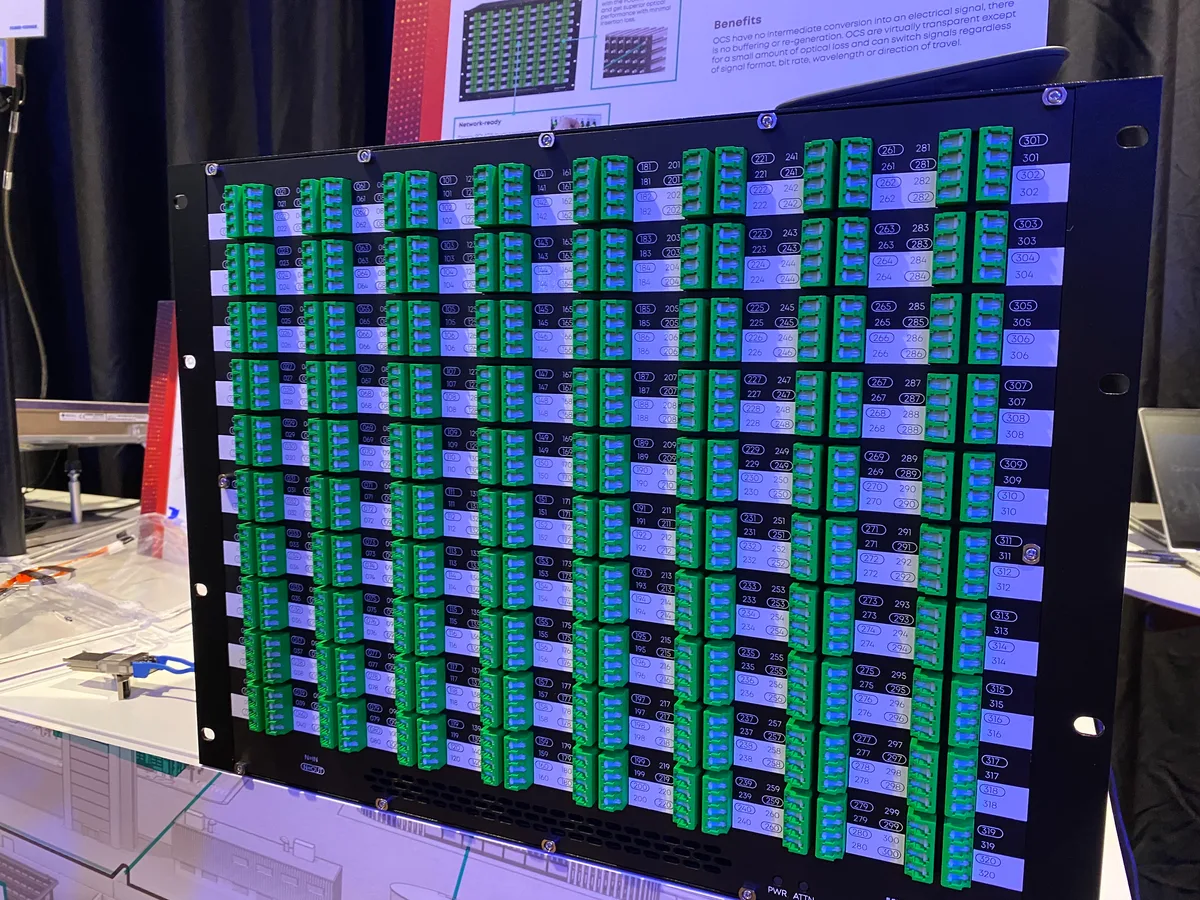Die Optical Circuit Switches (OCS): ein rechteckiger schwarzer Kubus. Die Front besteht aus grünen Steckerplätzen.